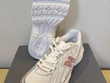 white and pink running shoes on display on a black box