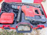 une boîte à outils rouge contenant des outils, posée par terre