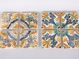 four square tiles with different designs on them sitting on a white surface