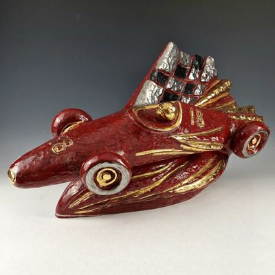 une petite voiture rouge ornée d'une décoration dorée