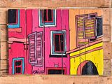painting of a colorful building on a wooden pallet on a wall
