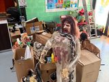 un faux zombie debout devant une pile de cartons