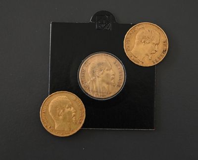 three gold coins are sitting on top of a black surface