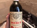 une personne tenant une bouteille de vin rouge à la main
