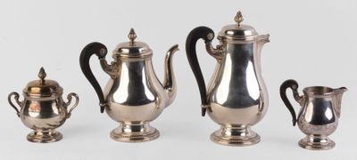 trois théières en argent et deux tasses en argent posées sur une table