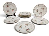 Plusieurs assiettes ornées de motifs floraux sont disposées sur une surface blanche