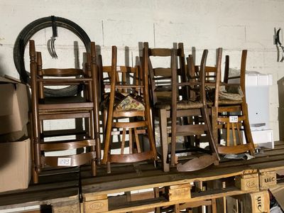 de nombreuses chaises en bois empilées les unes sur les autres dans une pièce