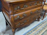 une commode en bois dans une pièce où sont accrochés des tableaux aux murs