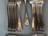 a lot of silver spoons and forks laid out on a table