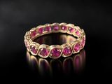 a gold ring with pink stones on a black surface