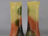 pair of vases with trees on them sitting on a table