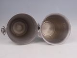 pair of silver plated cups with handles on a white surface