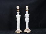 a pair of white and gold candlesticks with figures on them