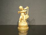 figurine en or représentant un Cupidon jouant de la harpe sur un fond noir