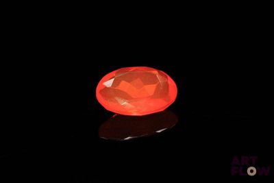 un diamant orange dans l'obscurité, dont le reflet se dessine sur le sol