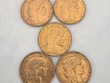 five gold coins are arranged in a triangle on a white surface