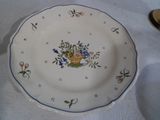 une assiette sur laquelle est posé un panier de fleurs, posée sur une table