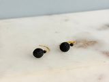 a pair of black and gold earrings on a marble surface