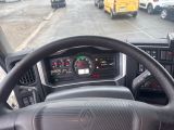 steering wheel of a truck on a city street with a school bus in the background