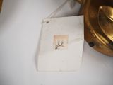 a picture of a gold lamp with a tag attached to it