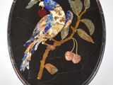 une assiette noire sur laquelle sont représentés un oiseau et un papillon