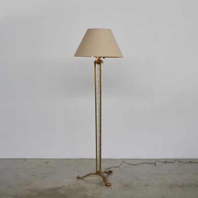 un lampadaire en laiton surmonté d'un abat-jour beige