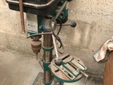 a drill on a stand in a garage with tools