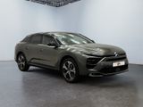 a grey car is parked in a large room with a white wall