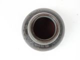 a black vase with a brown lid sitting on a white surface