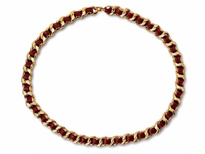a close up of a gold and red necklace on a white background