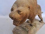 a statue of a lion that is on a piece of wood