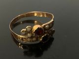 gold ring with garnetts and pearls on a black surface