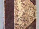 an old book sitting on top of a table covered in brown paper