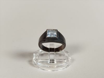 a black ring with a blue stone in it on a clear stand