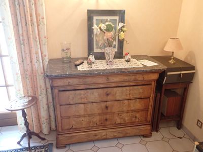 une photo d'une commode dans une pièce où il y a un tableau accroché au mur