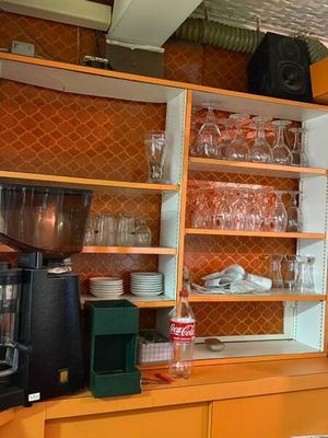 une cuisine avec des placards orange et une cafetière posée sur le plan de travail
