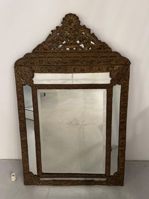 un miroir ancien avec un cadre en bois et un motif décoratif dans la partie supérieure