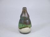un petit vase posé sur une surface blanche