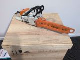 an orange and black chainsaw sitting on top of a wooden box