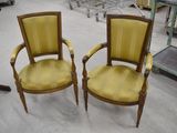 une paire de fauteuils rembourrés jaunes dans une pièce où l'on aperçoit de nombreux meubles à l'arrière-plan