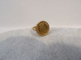 Gros plan sur une bague en or ornée d'une pièce de monnaie