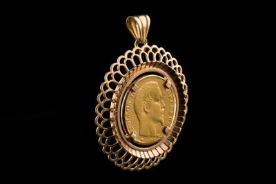 a close up of a gold coin in a pendant on a black background