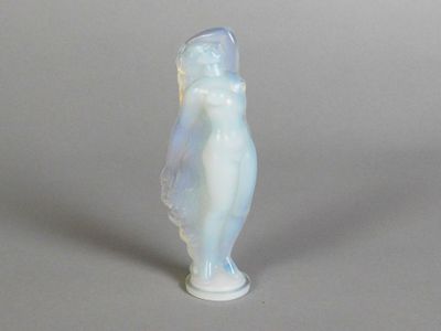 a small glass figurine of a woman on a gray surface
