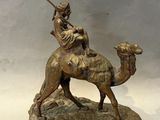 bronze statue of a man riding a camel with a spear in his hand