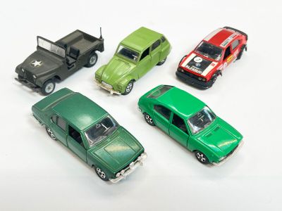 Plusieurs petites voitures sont alignées sur une surface blanche