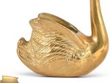 a gold swan figurine sitting next to a bottle of wine