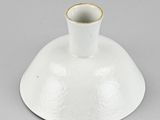 underside view of a white vase on a grey surface