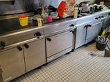 a large stainless steel kitchen with a lot of clutter on the counter