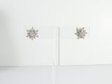 pair of white gold and diamond flower earrings on a white stand