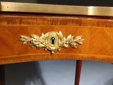 a small wooden table with a gold decoration on it